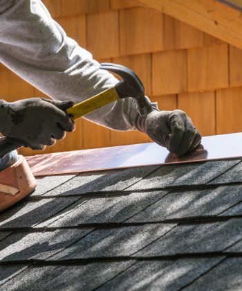 Installing new roof with hammer and copper edge flashing